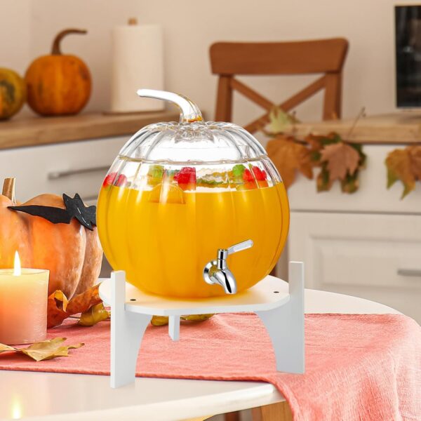 Seasonal pumpkin-shaped beverage dispenser with stainless steel tap and decorative wooden base.